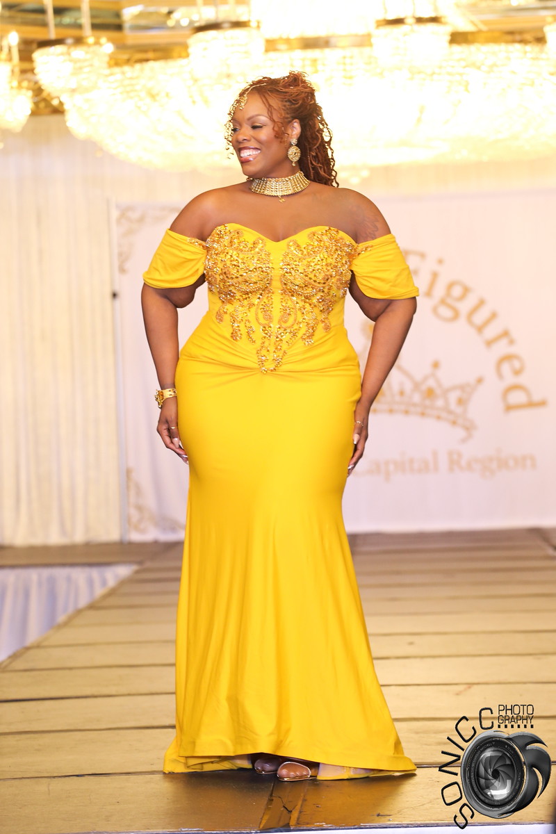 Queen Kris J on the pageant runway in a gold yellow evening gown at Miss Full Figured USA NCR